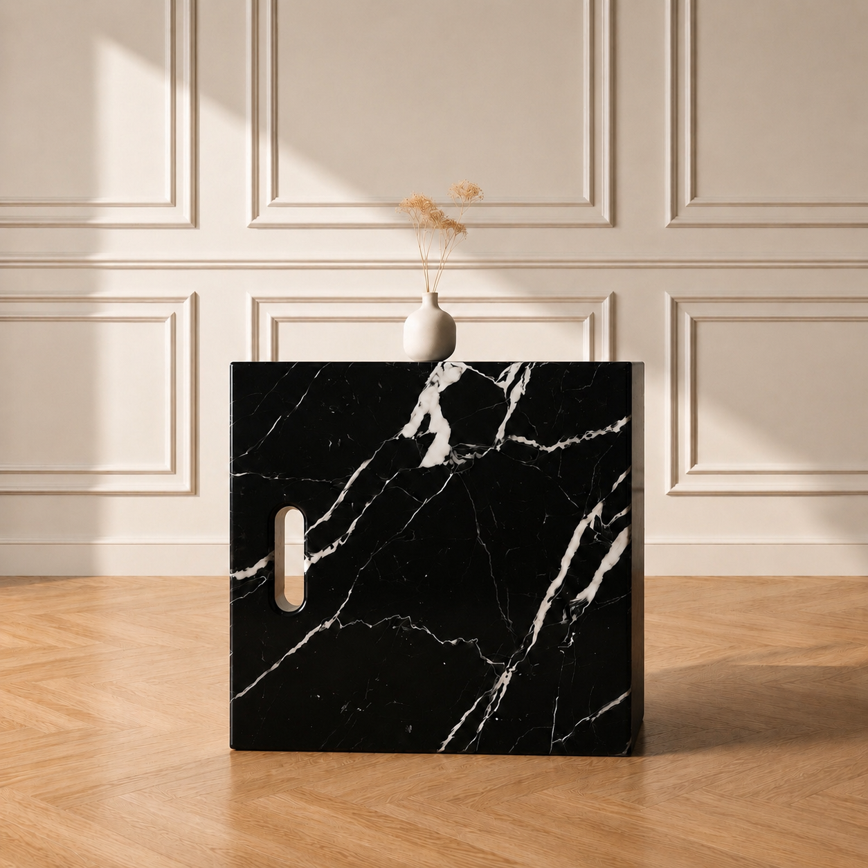 Iéna cube side table in Nero Antico marble, styled with a vase against a panelled wall on a chevron wood floor